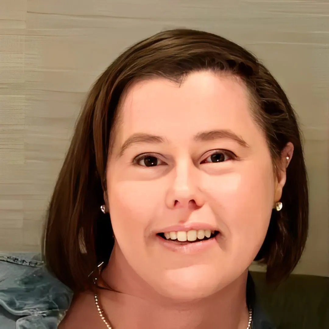 Here's an alt tag for the image: Smiling woman with brown hair and earrings.