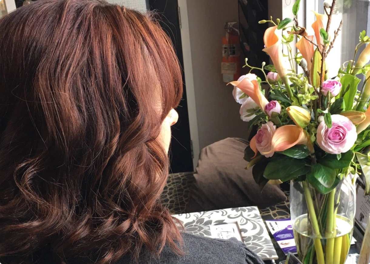 Woman with auburn hair admiring flowers.